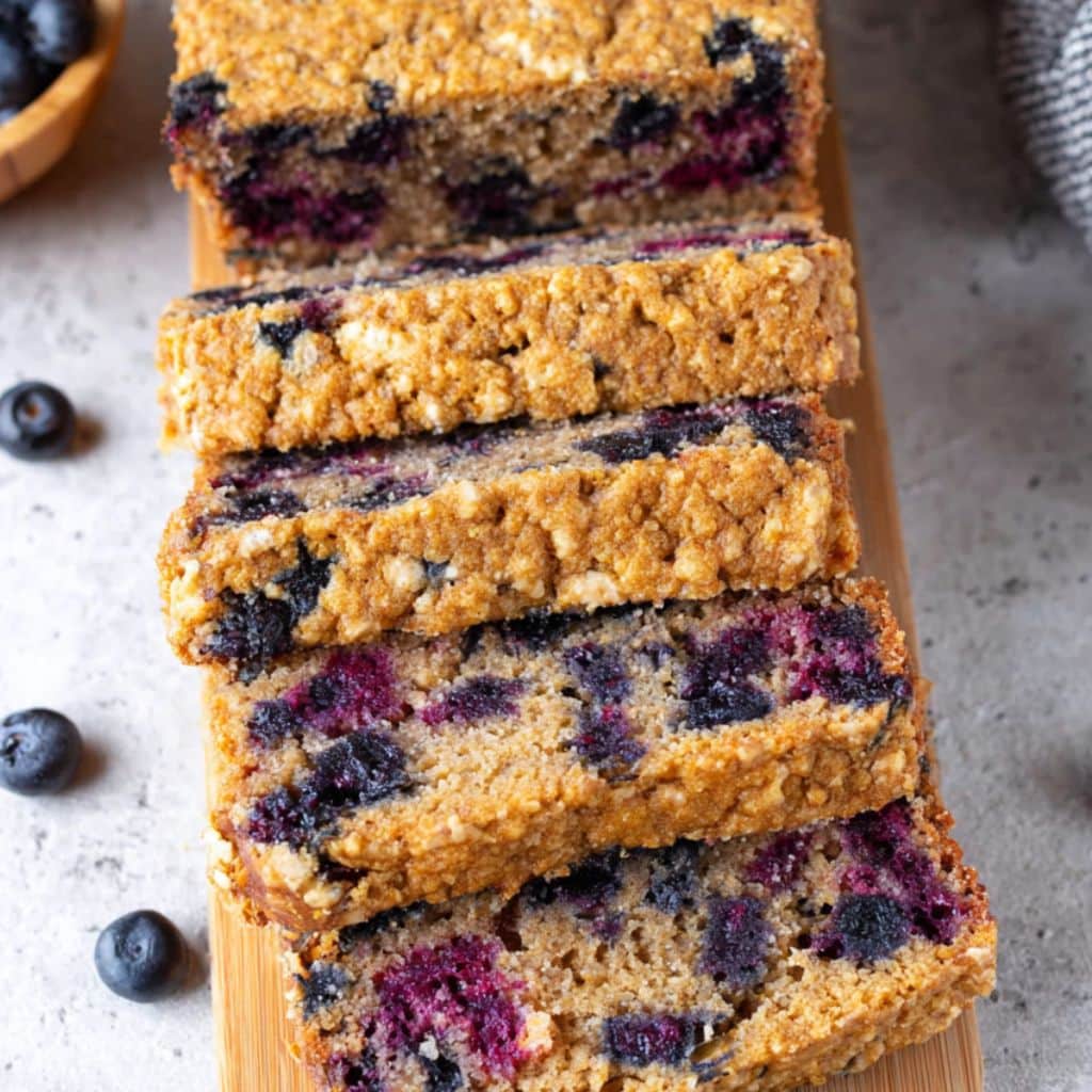 Stacked slices of blueberry oatmeal cottage cheese bread with juicy berries and golden crumb