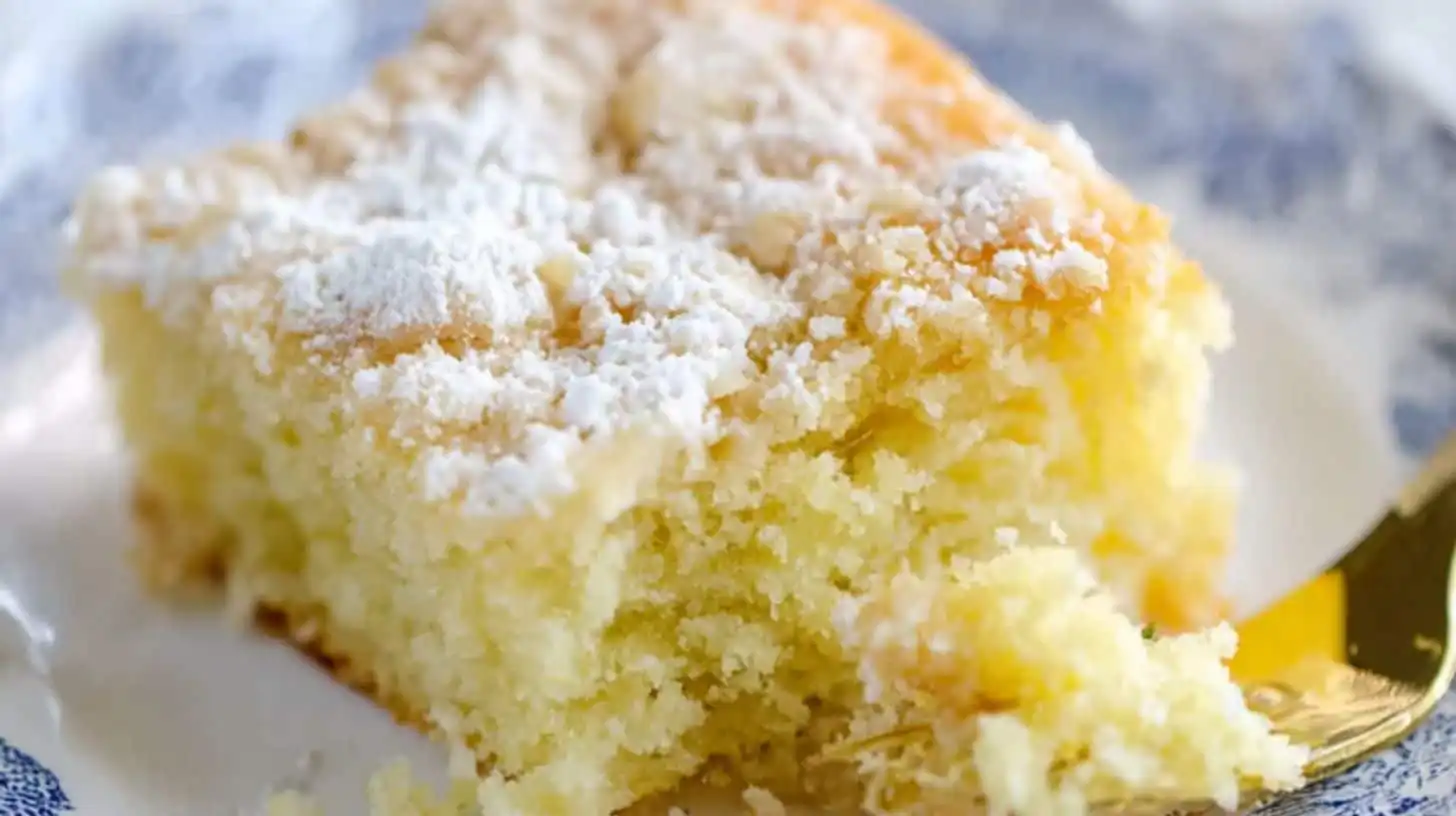 Close-up slice of lemon crunch cake with powdered sugar topping