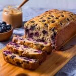 Blueberry cottage cheese bread sliced on a wooden board with peanut butter and fresh blueberries