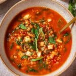 Bowl of high protein lentil soup with spinach and fresh herbs