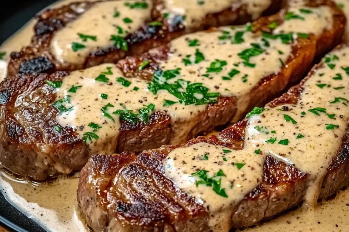 Ribeye steak in skillet covered with creamy garlic sauce and chopped parsley