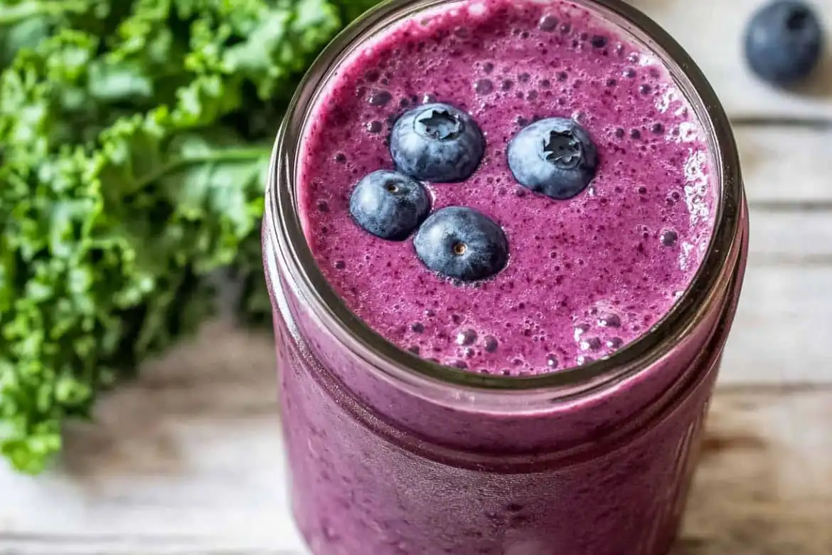 Kale and blueberry smoothie in a glass jar topped with fresh blueberries