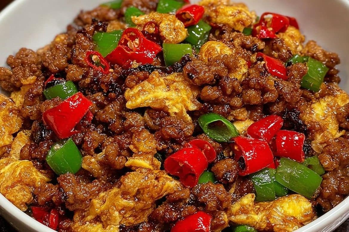 Minced meat and egg stir-fry with red and green chilies in a white bowl