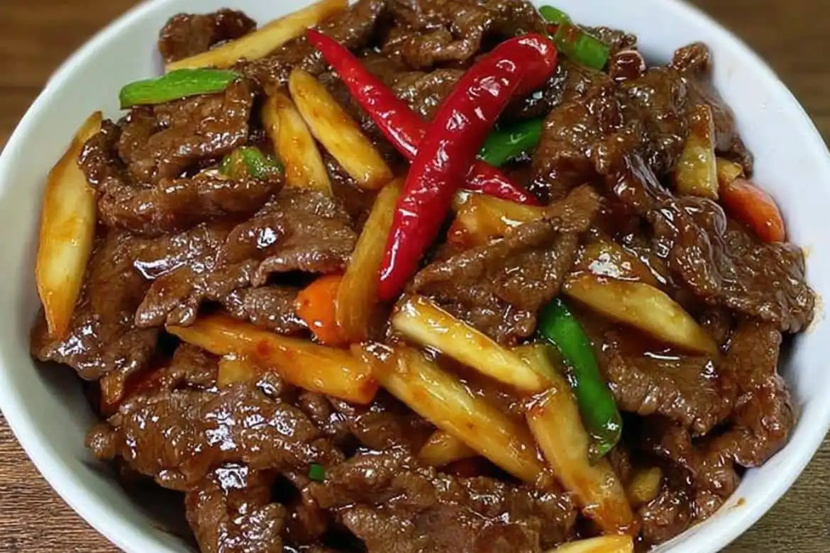 Stir-fried beef with bamboo shoots and chilies served in a white bowl