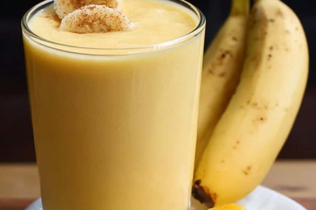 Banana mango smoothie in a glass with banana slices on top