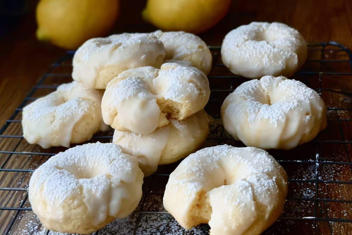 Homemade Italian Lemon Cookies with glaze and powdered sugar cooling on rack