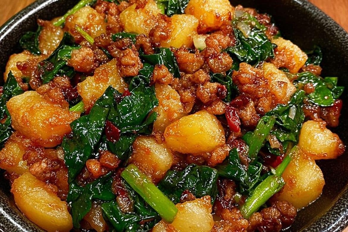 Stir-fried potatoes and leafy greens with minced meat in a black bowl