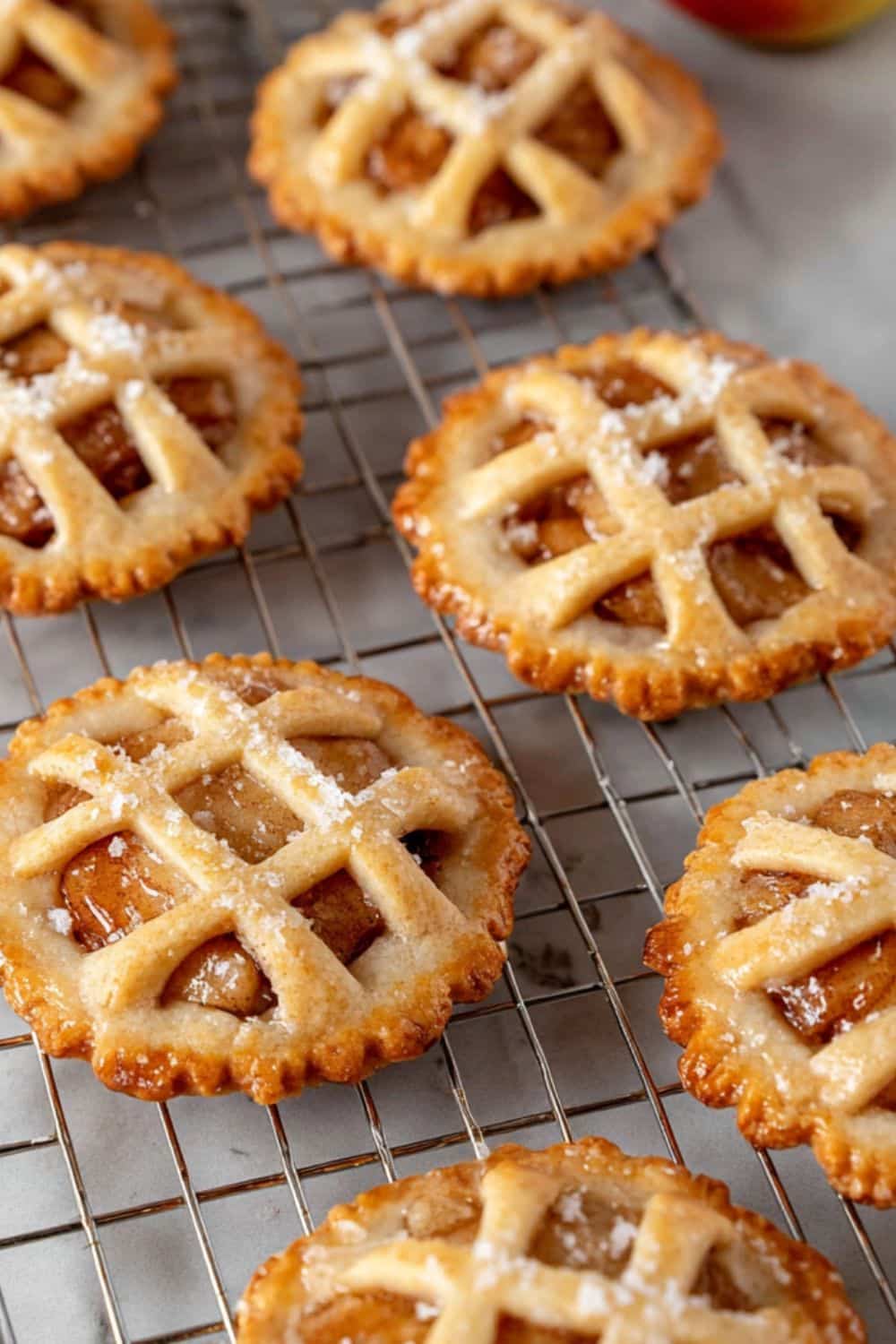 Apple pie cookies cooling on a wire rack, with a golden lattice crust.