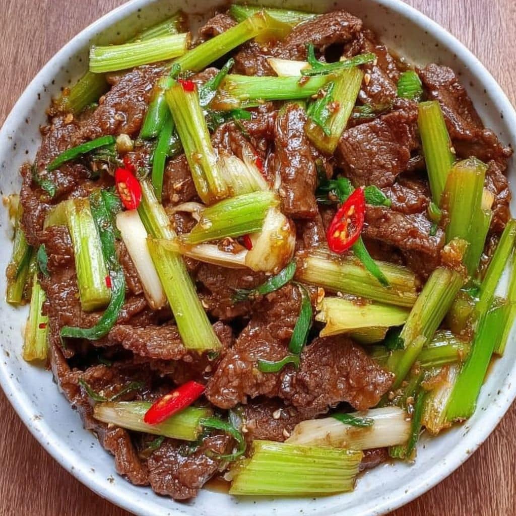Top view of beef and celery stir-fry in a ceramic bowl with red chili
