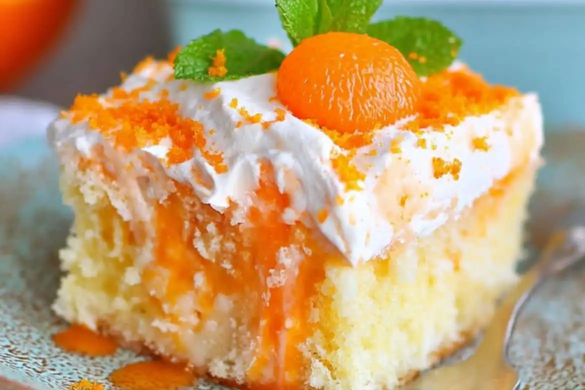 Slice of orange creamsicle cake with whipped mandarin topping and orange zest