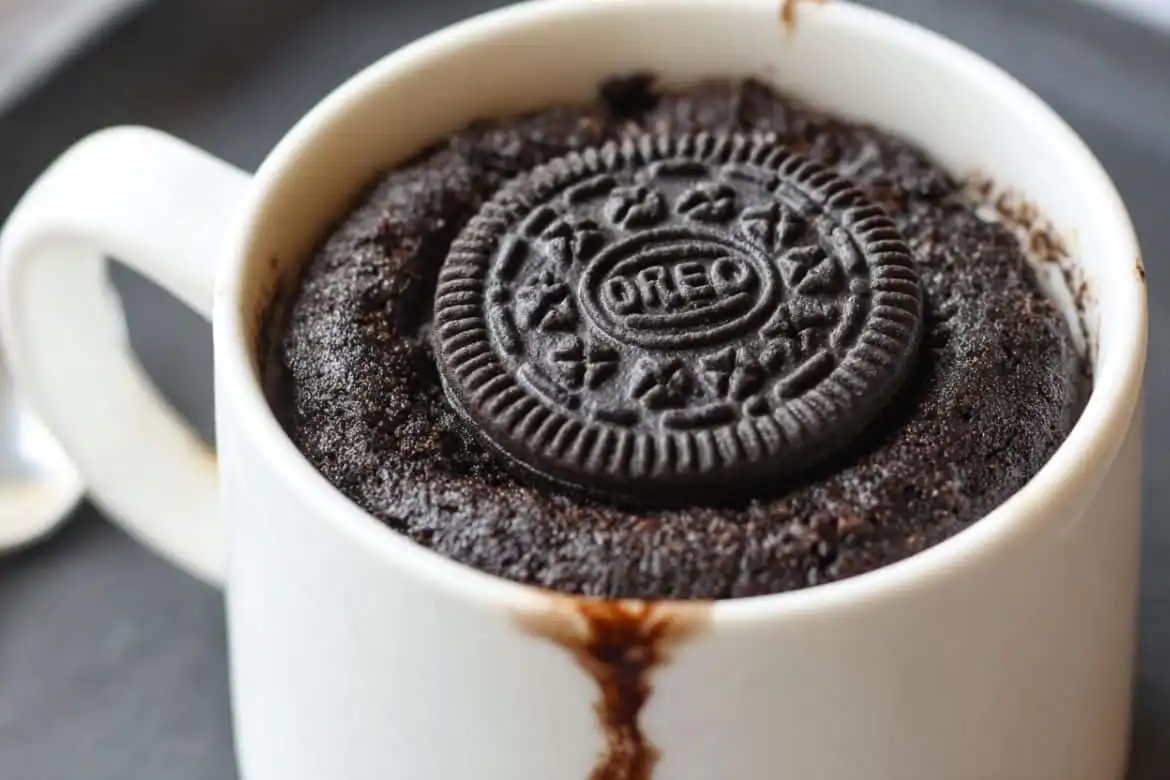 Oreo mug cake recipe served in a white mug with a whole Oreo on top