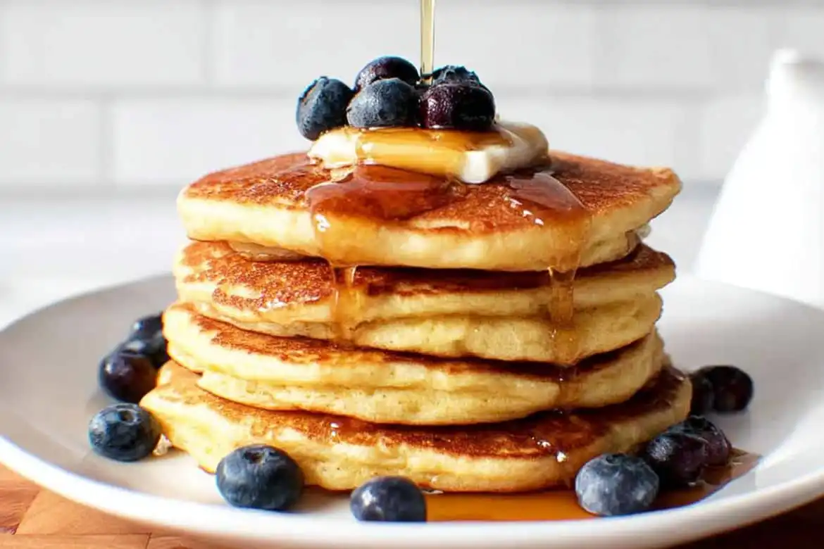 Fluffy almond flour pancakes stacked with butter, blueberries, and maple syrup