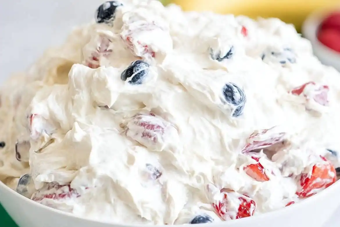 creamy cheesecake fruit salad with strawberries and blueberries in a white bowl