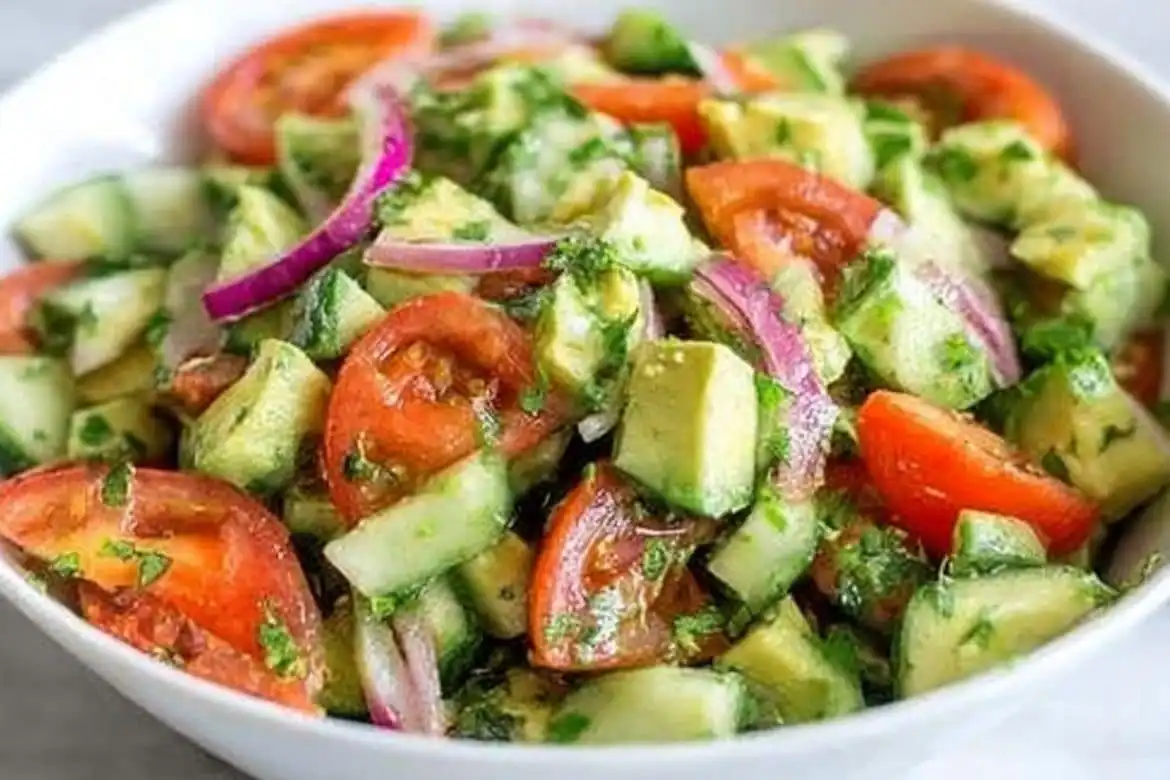 cucumber tomato avocado salad with red onion in white bowl