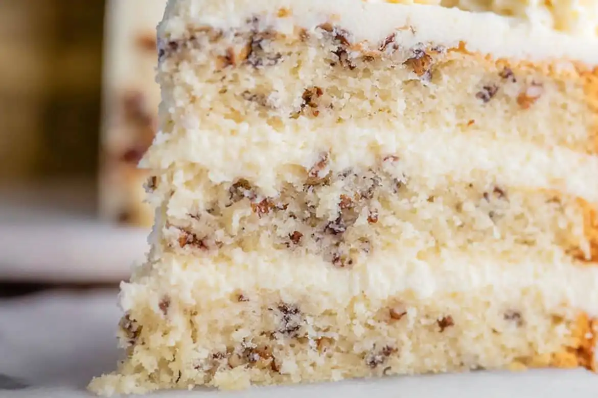 Italian cream cake slice with cream cheese frosting and chopped pecans