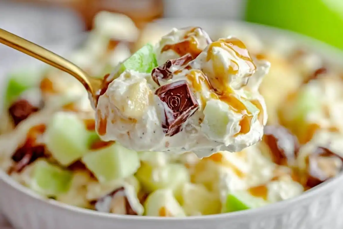 Spoonful of Snickers apple salad with chopped apples, Snickers, and caramel drizzle