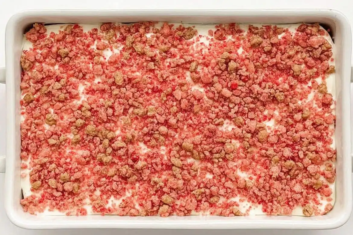 Strawberry crunch cake with golden Oreo and freeze-dried strawberry topping in white baking dish