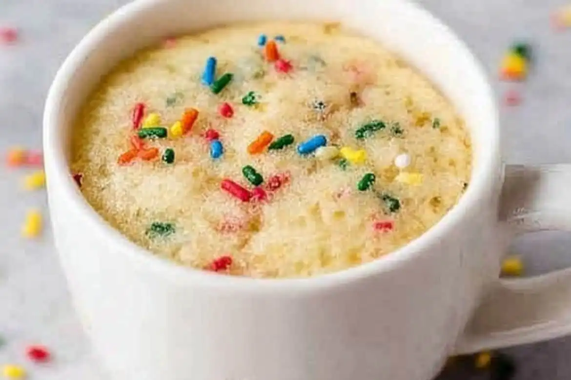 Vanilla Mug Cake in white mug topped with colorful sprinkles