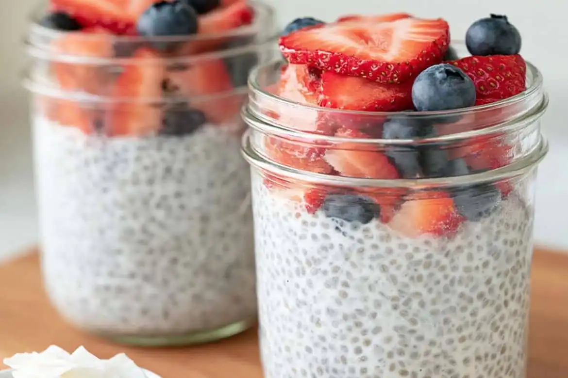 chia seed pudding in glass jars topped with strawberries and blueberries
