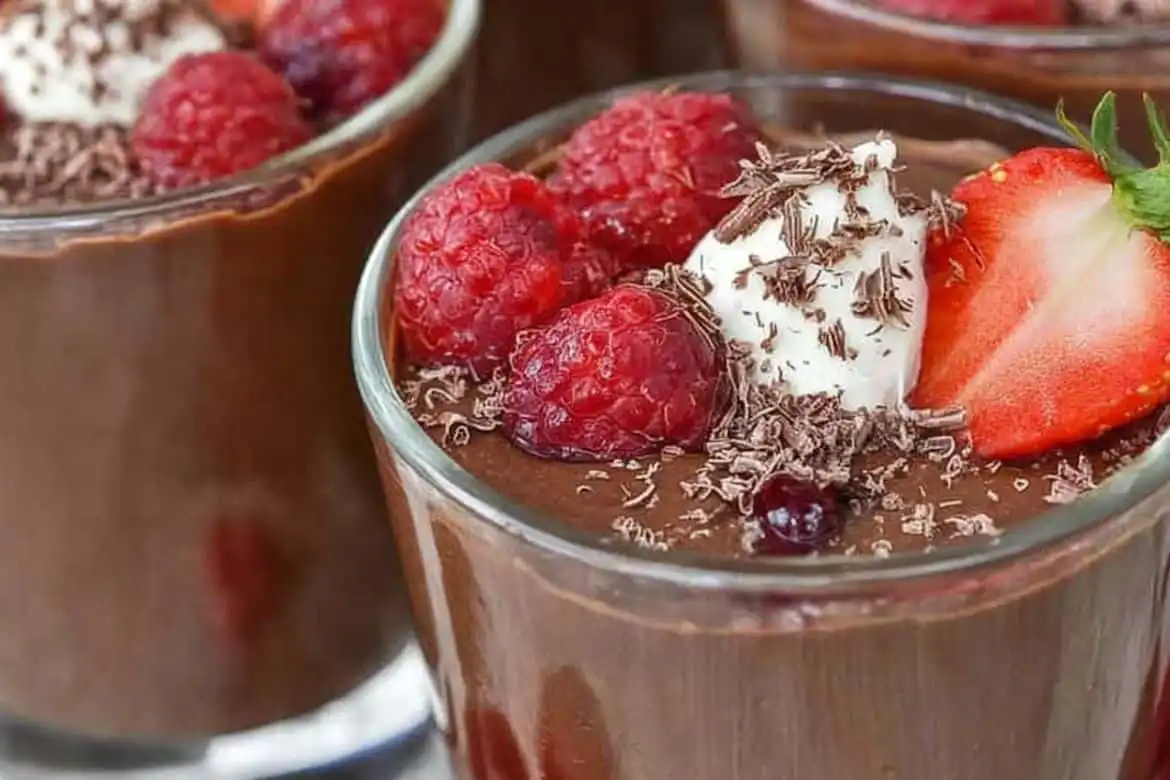 Homemade chocolate pudding with fresh berries and whipped cream