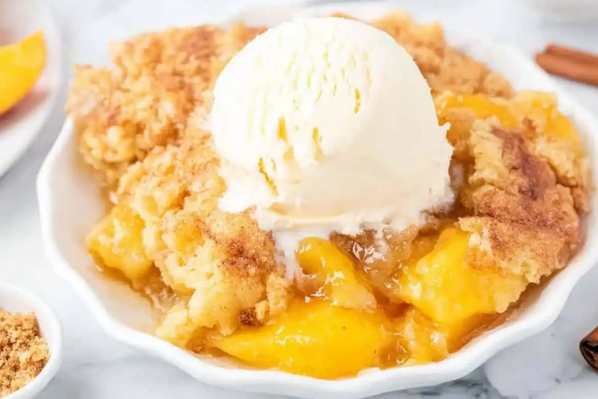 Peach cobbler dump cake served with vanilla ice cream on top