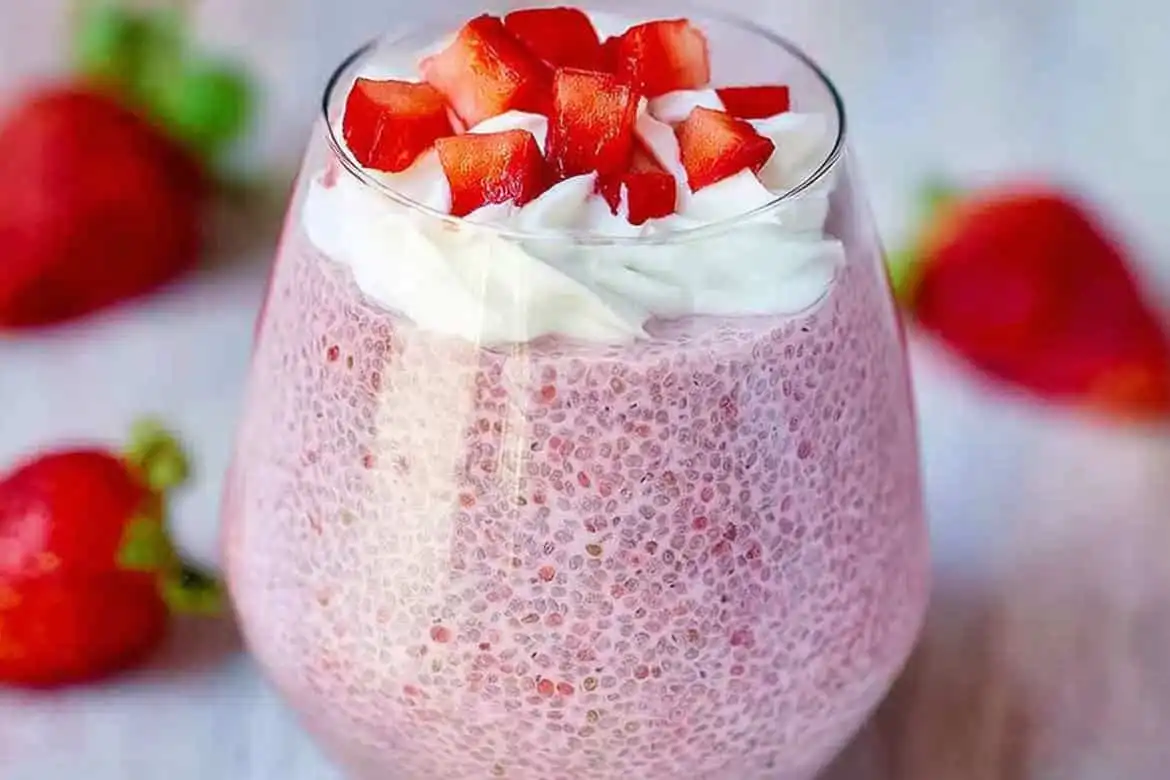 Strawberry chia seed pudding in a glass topped with whipped cream and fresh diced strawberries