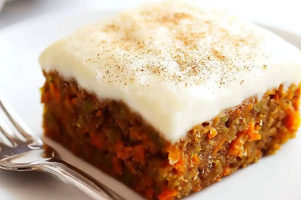 Carrot cake bars with Cream Cheese Frosting topped with cinnamon on a white plate