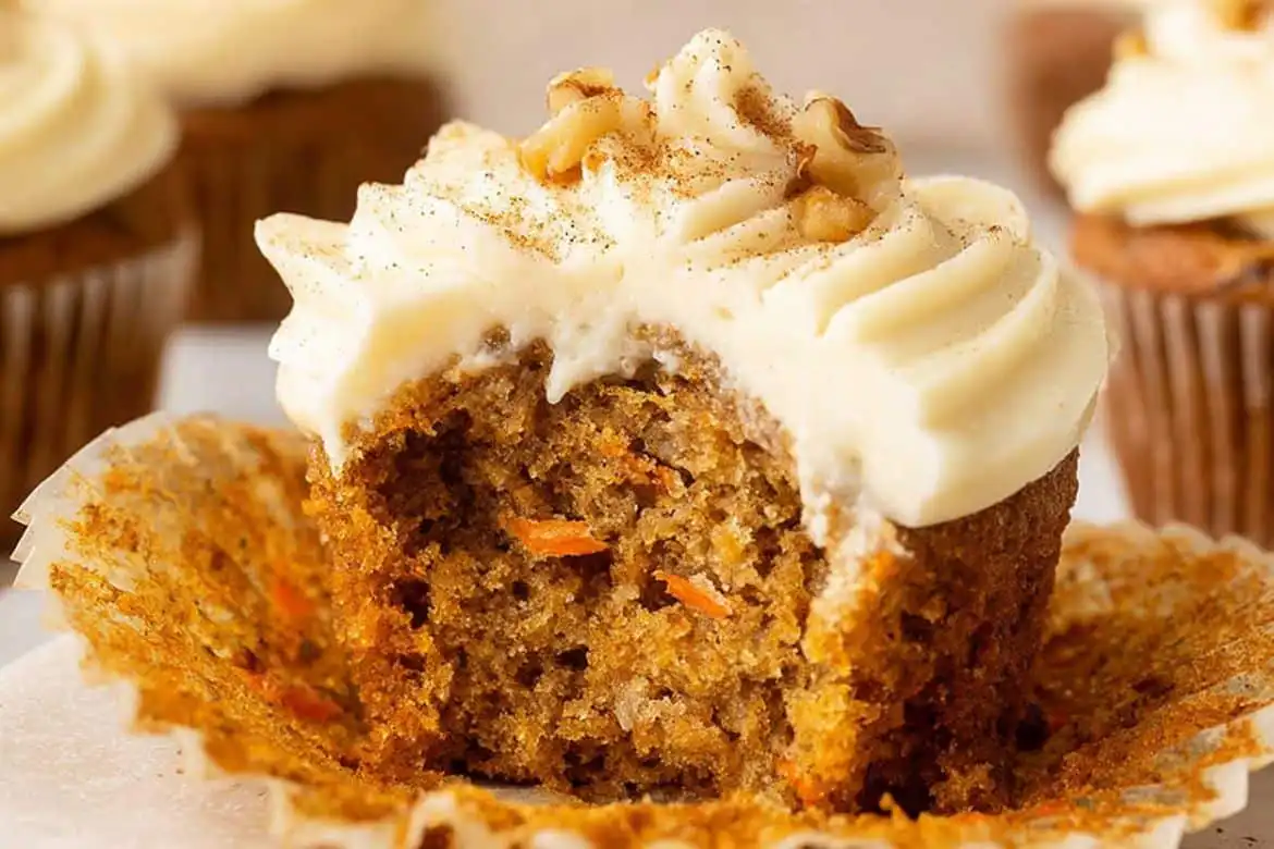 Carrot cake muffin with cream cheese frosting and visible grated carrots inside